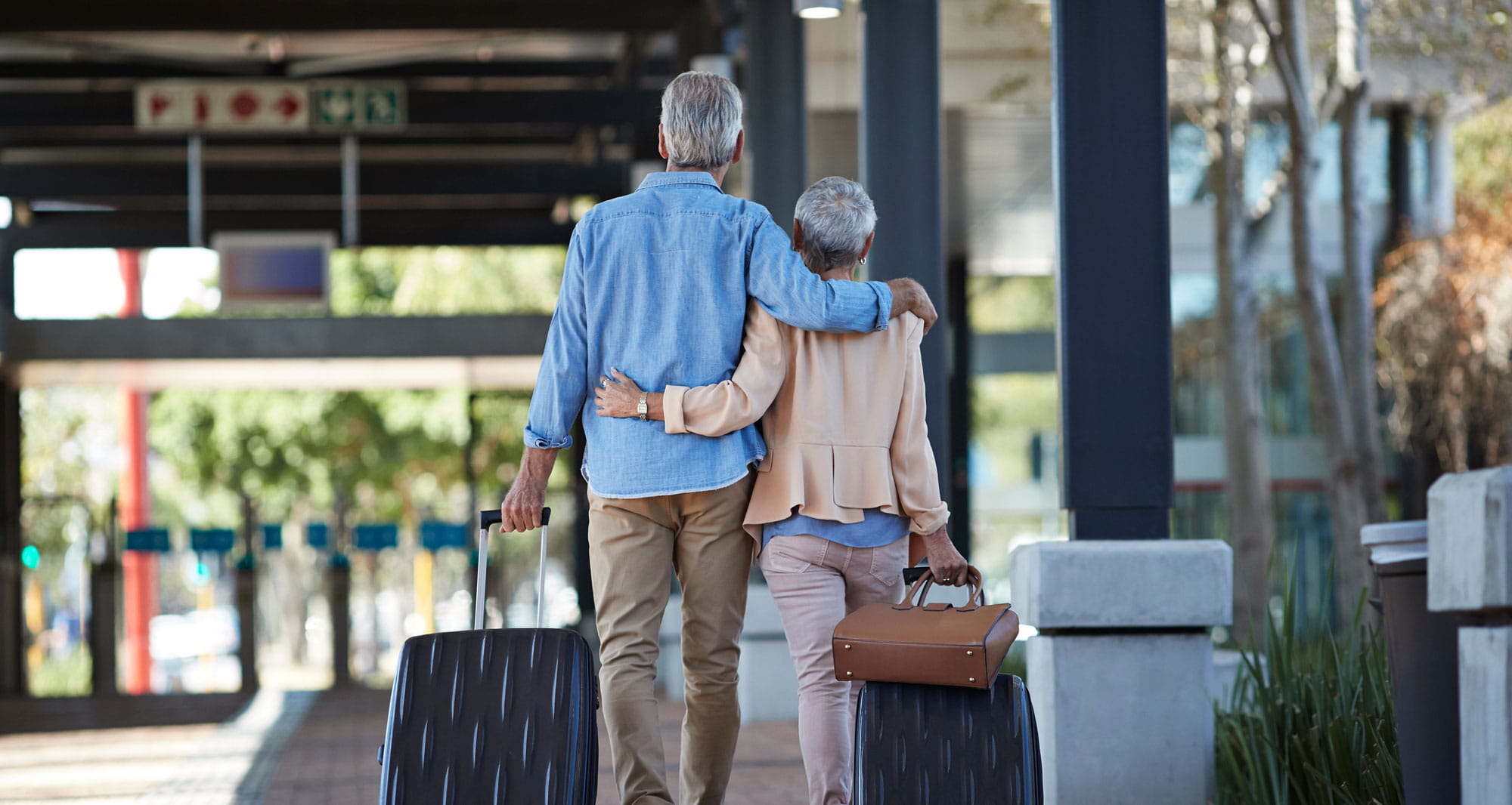 A couple walks with their bags at the airport.