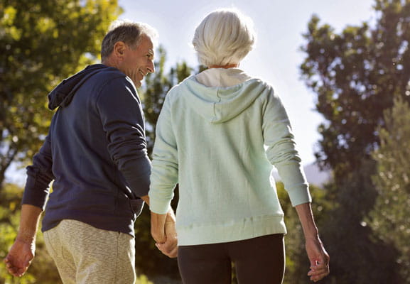 A couple in workout clothes walk with their back turned to the camera.