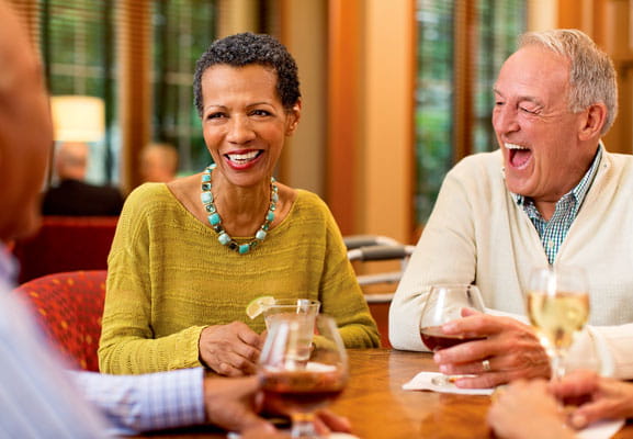 A man and woman laugh together over cocktails.